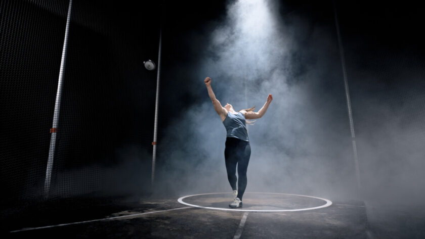 iStock Signature: Dare to Stand Out in a World Full of Ordinary Visuals Female athlete throwing discus while practising on track at night in arena. iStock Signature photo